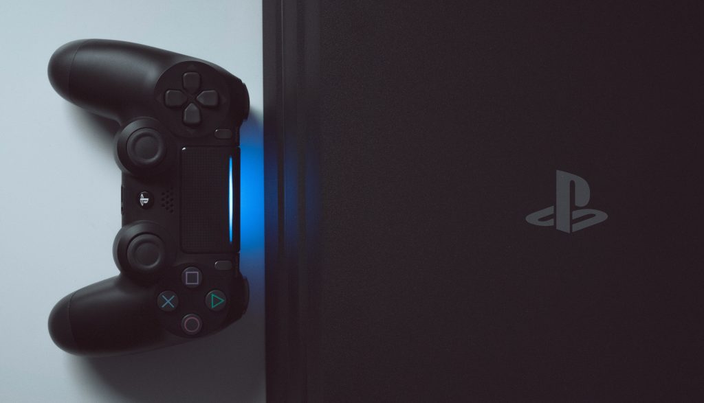photo of a Playstation 4 together with a controller